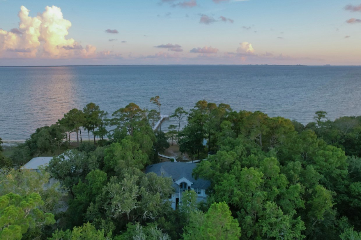 Aerial view of a coastal Florida property surrounded by pines at sunset